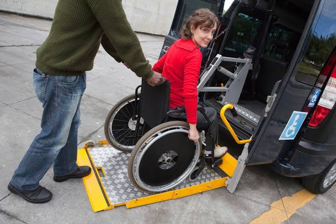 A wheelchair parked in front of a van.